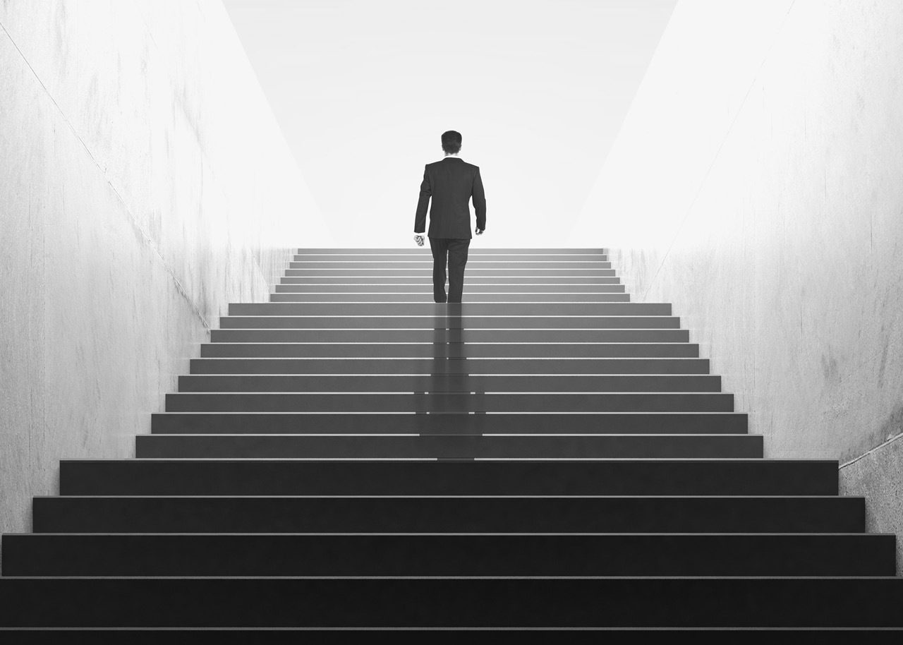 black and white image of business man walking up stairs